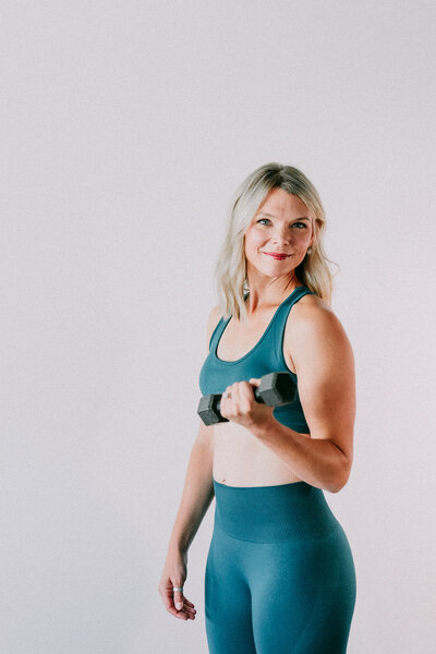 Kelsey Wickenhauser, a Christian health coach, in a blue workout outfit, showcasing faith-fueled fitness through weightlifting.