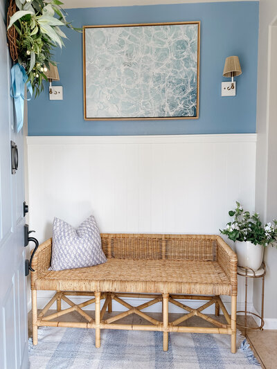 a wicker bench in front of a blue and white wall