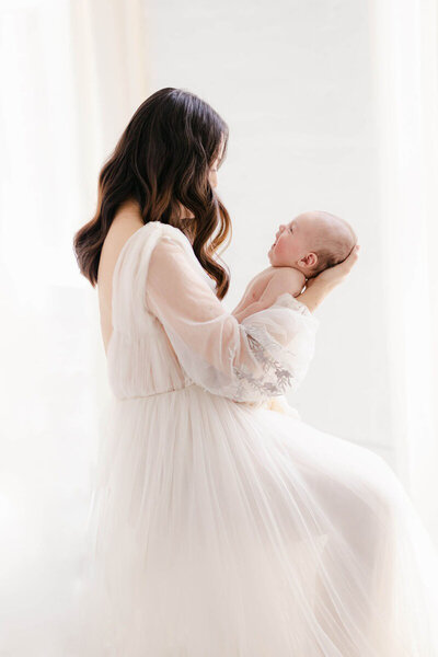 Studio portrait by a San Francisco Bay Area newborn photographer, baby in wrap being held by mom.
