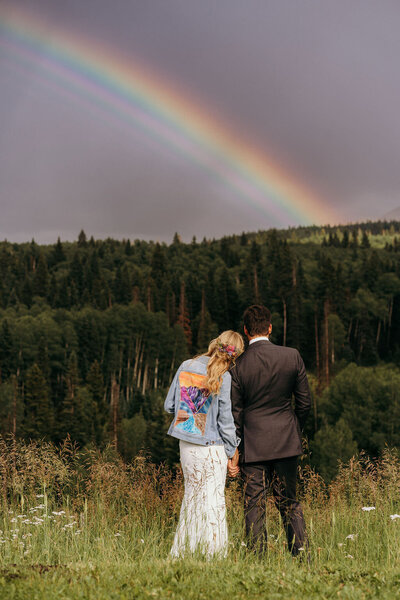 photo of man and woman standing outside looking up at a rainbow taken by Elopement photographer Jackson Hole WY