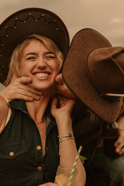 A warm and joyful image of a newly married husband kissing his wife on the cheek, wearing akubra hats captured by Sunshine Coast wedding photographer.