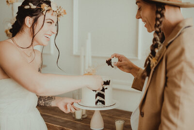 two brides about to feed each other a bite of cake