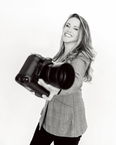 woman smiling, holding her camera towards the lens