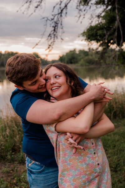 Man wraps his arms around woman from behind and they smile at each other.