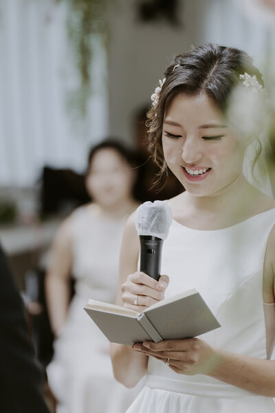 a Korean bride dressed in a white wedding gown is reciting her vows at her wedding in Seoul, South Korea