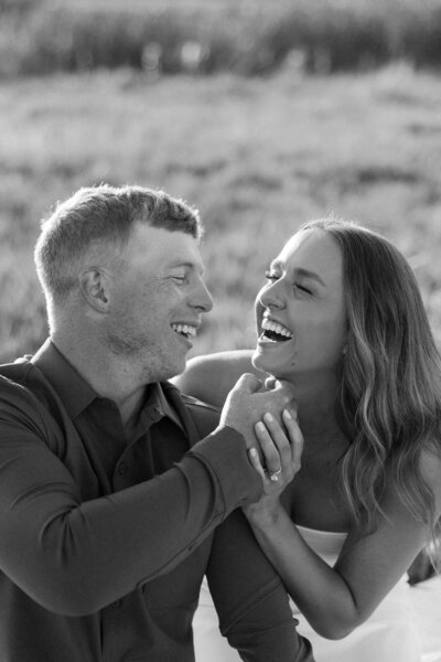 Black and white photo of a couple laughing together during an intimate moment.