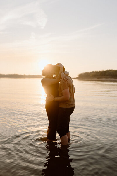 A romantic couple kissing in the water during summer.