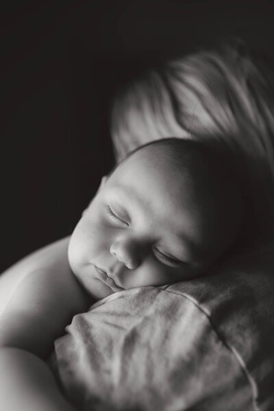 Black and white portrait of a sleeping baby boy with his cheek resting on his mothers shoulder. Captured in Revelstoke by Brittany Danielle.
