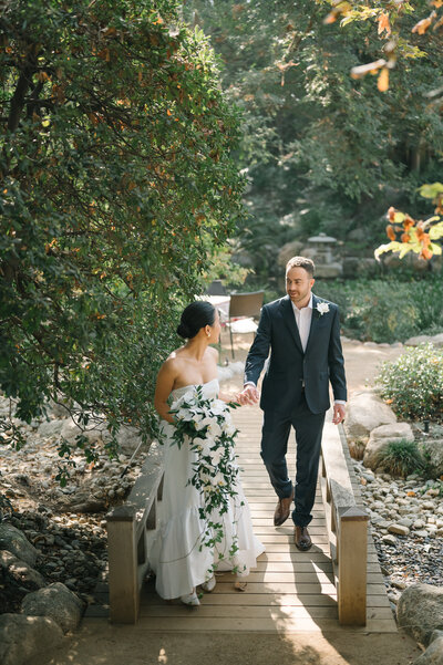 couple crossing bridge in a Japanese garden in Pasadena with maple leaves