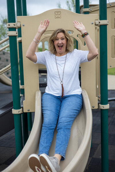 woman going down slide with arms up