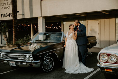 bride and groom posing by car