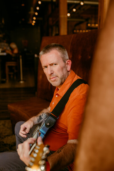 Kerry holding his guitar in a professional dating portrait — highlighting personality and genuine expression for online dating success.