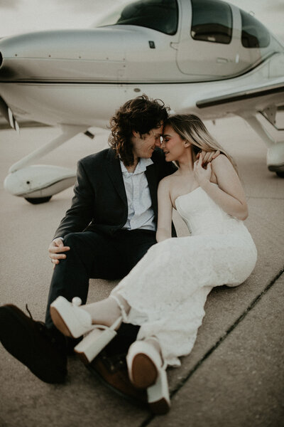 Engaged couple snuggling in front of a plane during their engagement session in Jacksonville, Florida
