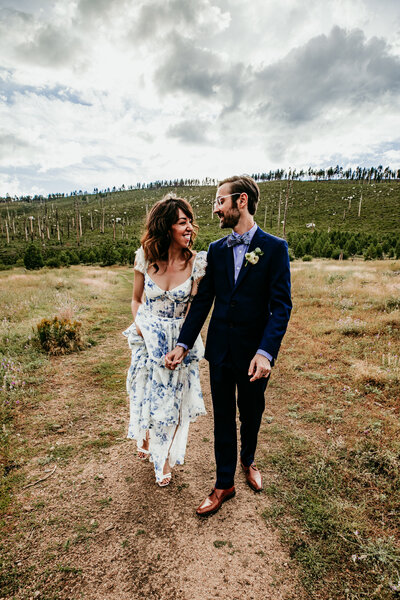 Bride and groom walking hand-in-hand through a grassy field near Lake Tahoe during their elopement.