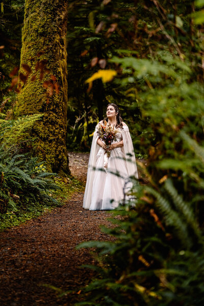 A bride walks through a lush rainforest for their Oregon Coast elopement.