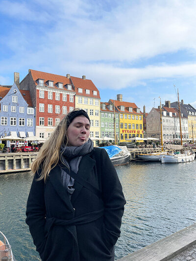 Female entrepreneur by colorful canal houses in Copenhagen, showcasing solo travel lifestyle and creative business