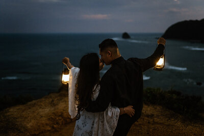 bride and groom are facing away from the camera, holding lanters up by their sides while their faces look towards each other to go in for a kiss