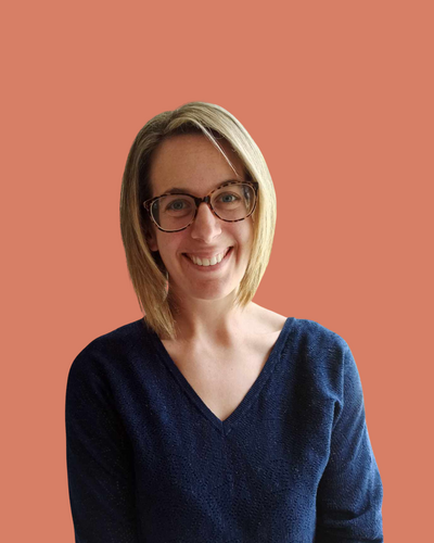 Portrait d’Aurélie Gignon, femme souriante aux lunettes et pull bleu marine, photographiée sur fond uni vert pour le blog de Lili Créa Design, consultante en branding et webdesign en Loire-Atlantique