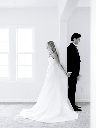bride and groom holding hands behind door frame by wedding planners in minneapolis minnesota