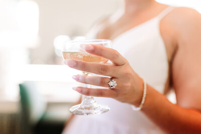 Bride holding glass of champagne showing wedding ring