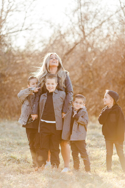 Mom of four boys standing in woods grouped together laughing