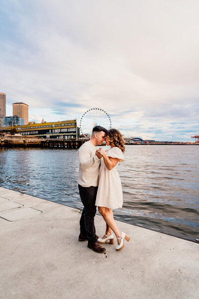 a couple dancing in front of the seattle ferris wheel next to pike place