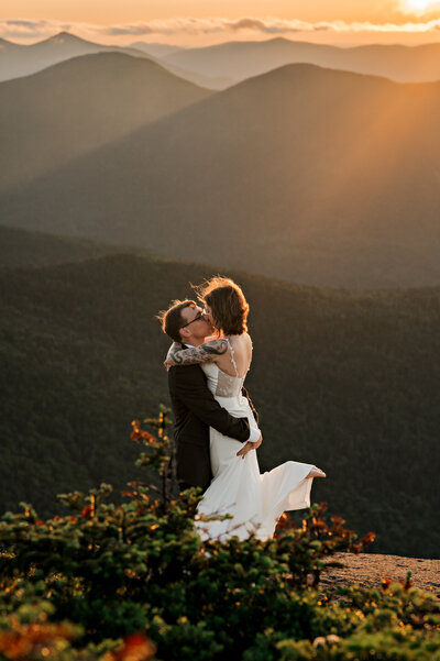 A couple has their first dance on top of a high peak in the Adirondack mountains at sunset. 