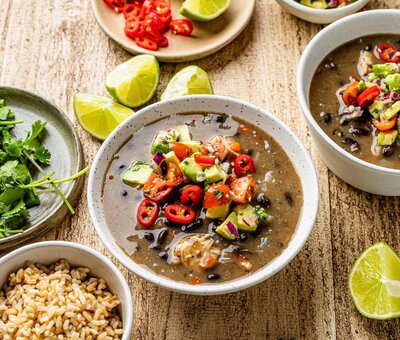 Mexican-inspired black bean and chicken chilli with avocado salsa and lime