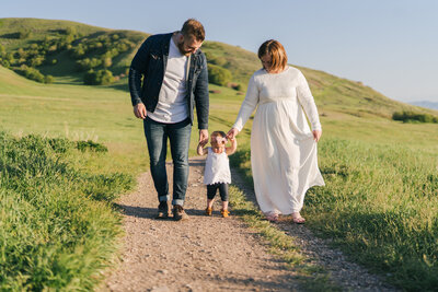 Nick with his wife and daughter, walking down a dirt path in a field