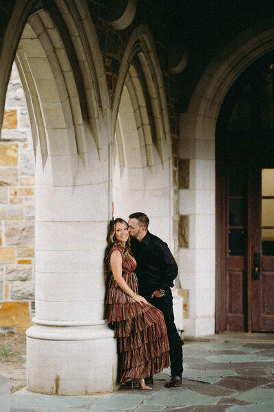 Couple kissing on for their engagements photos in a beautiful architecture. 