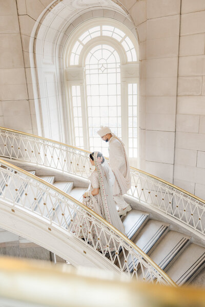 bridal portrait of Indian couple on grand staircase with floor to ceiling windows