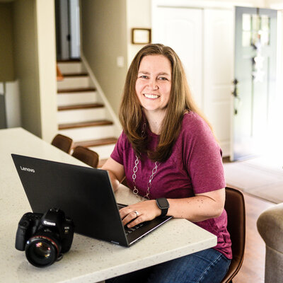 Danielle Hardesty sitting at counter on laptop smiling | Chicagoland brand photographer