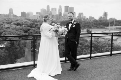 black and white wedding image of bride and groom outside in front of a cityscape shot by tom thornton photography in minnesota