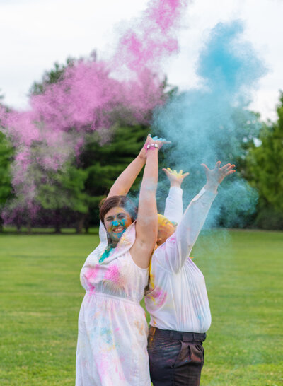 LGBTQ+ couple, Ivalee and Kara, joyfully throwing up colored powder