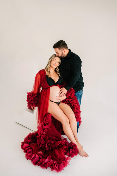 husband kissing pregnant wife's head in Springfield MO matenrity photography studio