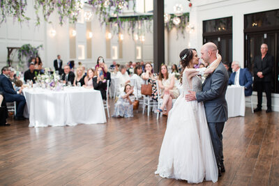 Bride and groom sharing their first dance in front of friends and family