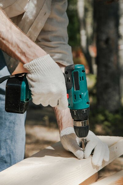 A Dallas renovation contractor using a drill as a key tool for renovating a house. The contractor is dressed in construction uniform and protective gloves, highlighting professionalism and expertise in home renovation projects.