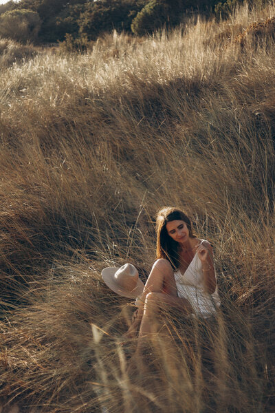 a young woman wearing a white dress sitting in a field