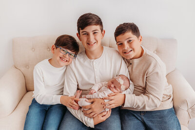 Three brothers holding baby sister.