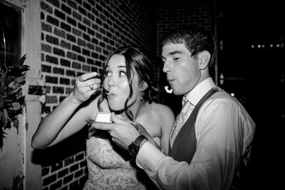 Black and white flash photo of bride and groom eating cake at Austin wedding reception