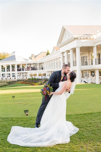 bride and groom doing a dip kiss on golf course
