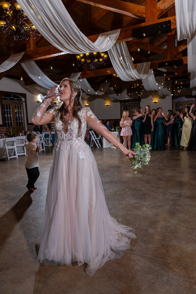 A newlywed holding a bouquet and drinking champagne 