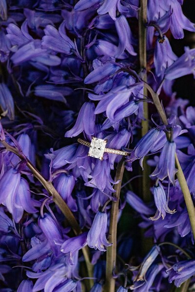 Square cut rose gold wedding ring on a  bunch of purple flowers