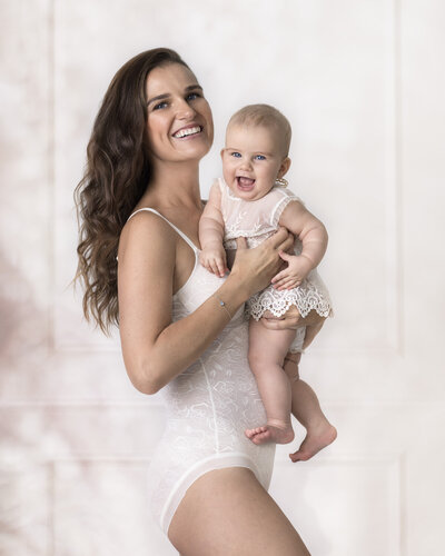 Gorgeous portrait of a smiling mother holding her baby in London studio