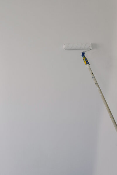 Rouleau de peinture peignant un mur blanc