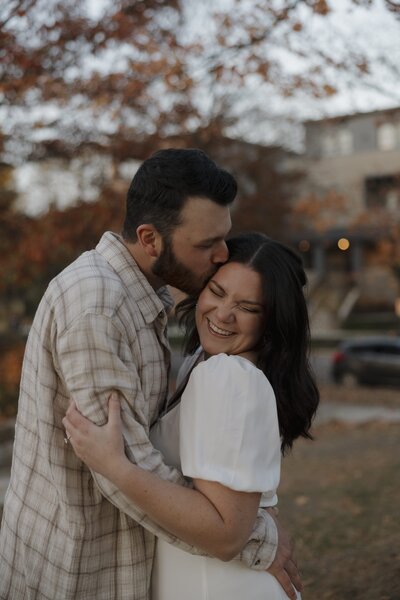 man kissing his fiiance on her forehead