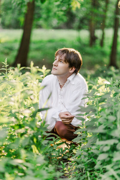 male sitting in tall greenery during golden hour in upstate ny