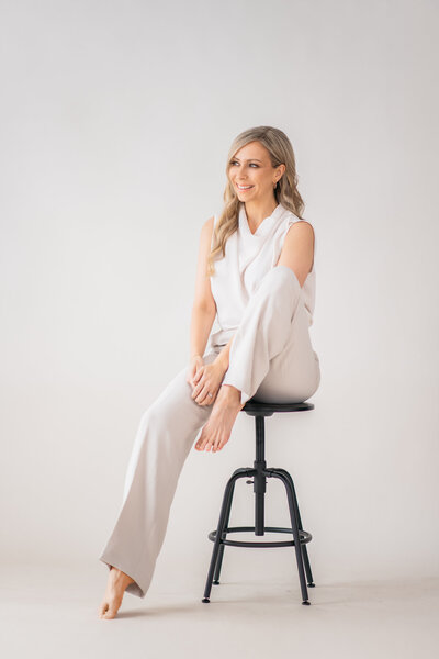 Dr. Tracy sitting on stool smiling