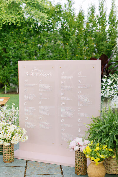 Acrylic seating chart with white calligraphy mounted on blush pink wood board for Lion Rock Farm wedding in Connecticut