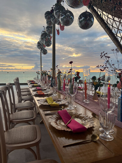 Elegant dinner table set for a destination wedding, featuring stunning ocean views in the background.